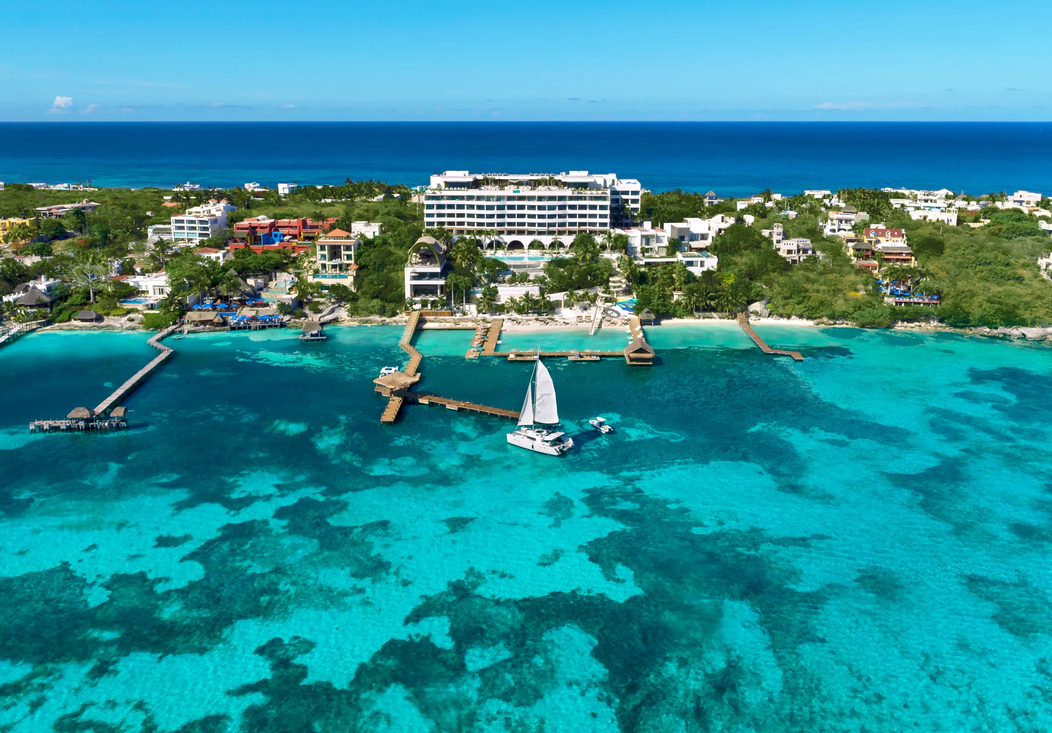 Aerial view of Impression Isla Mujeres by Secrets with turquoise waters, private docks, and beachfront luxury resort.