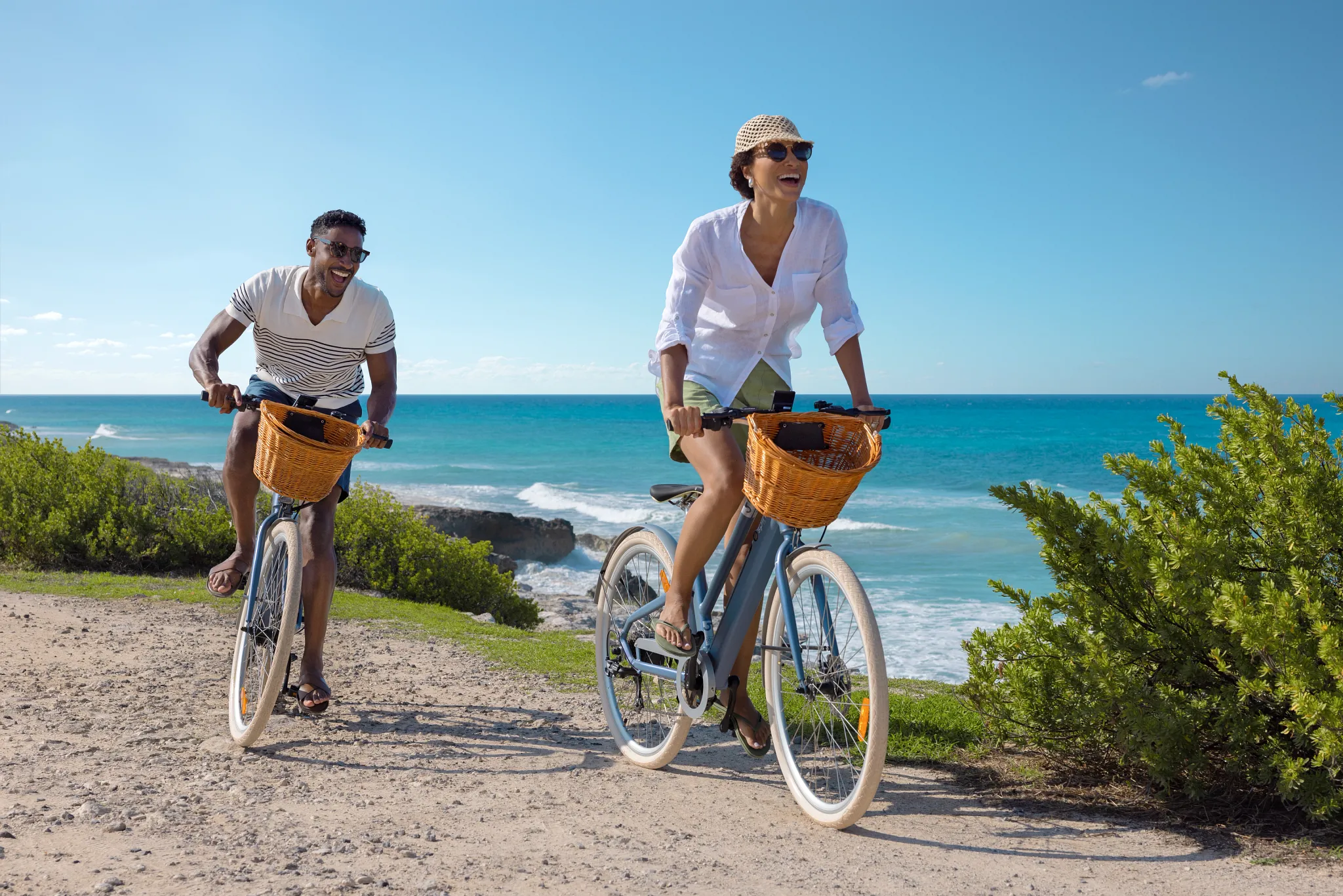 Couple riding bicycles along a scenic ocean path near Impression Isla Mujeres by Secrets, enjoying a relaxed island adventure.