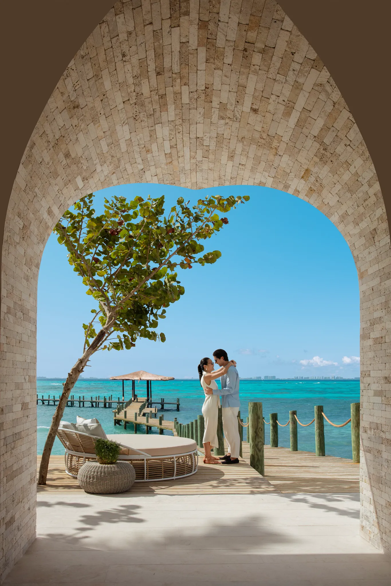 Couple embracing under a stone arch with ocean views and private dock at Impression Isla Mujeres by Secrets.