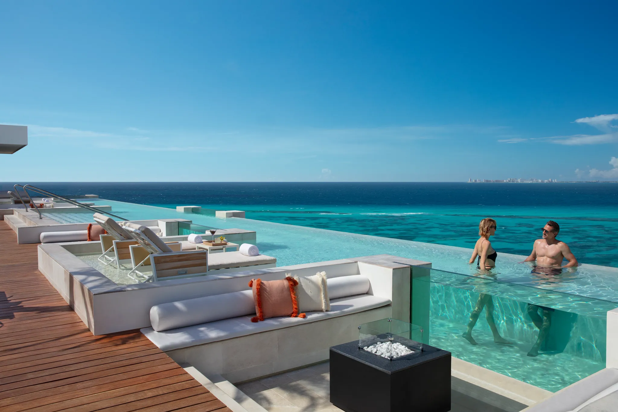 Couple relaxing together in a rooftop pool overlooking the ocean at Impression Isla Mujeres by Secrets.