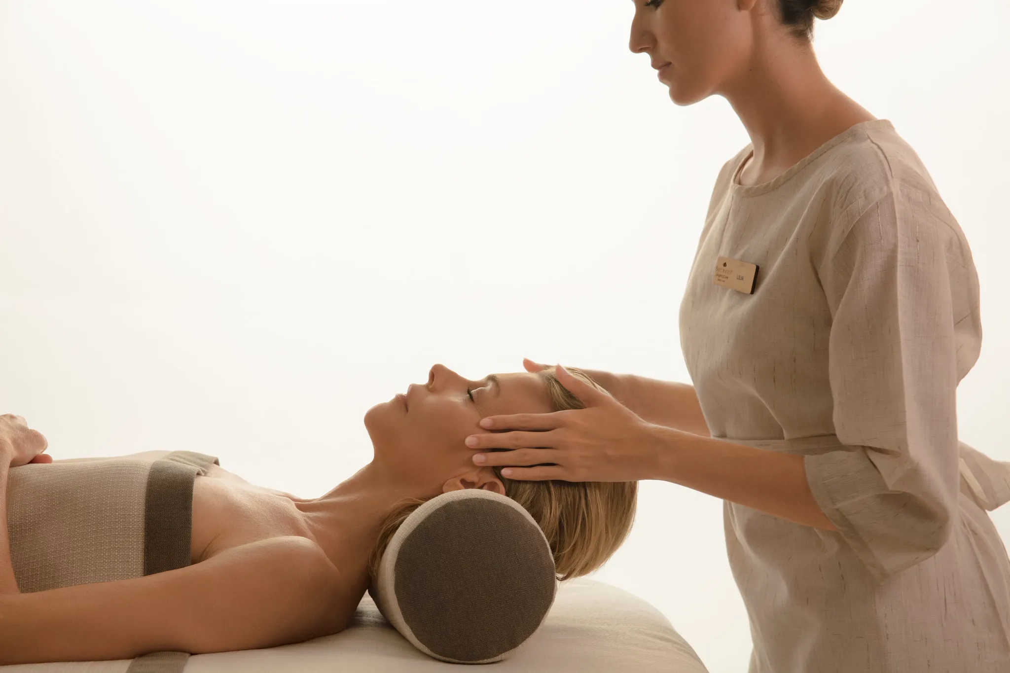 Therapist performing facial massage on guest in spa treatment room at Impression Isla Mujeres by Secrets.