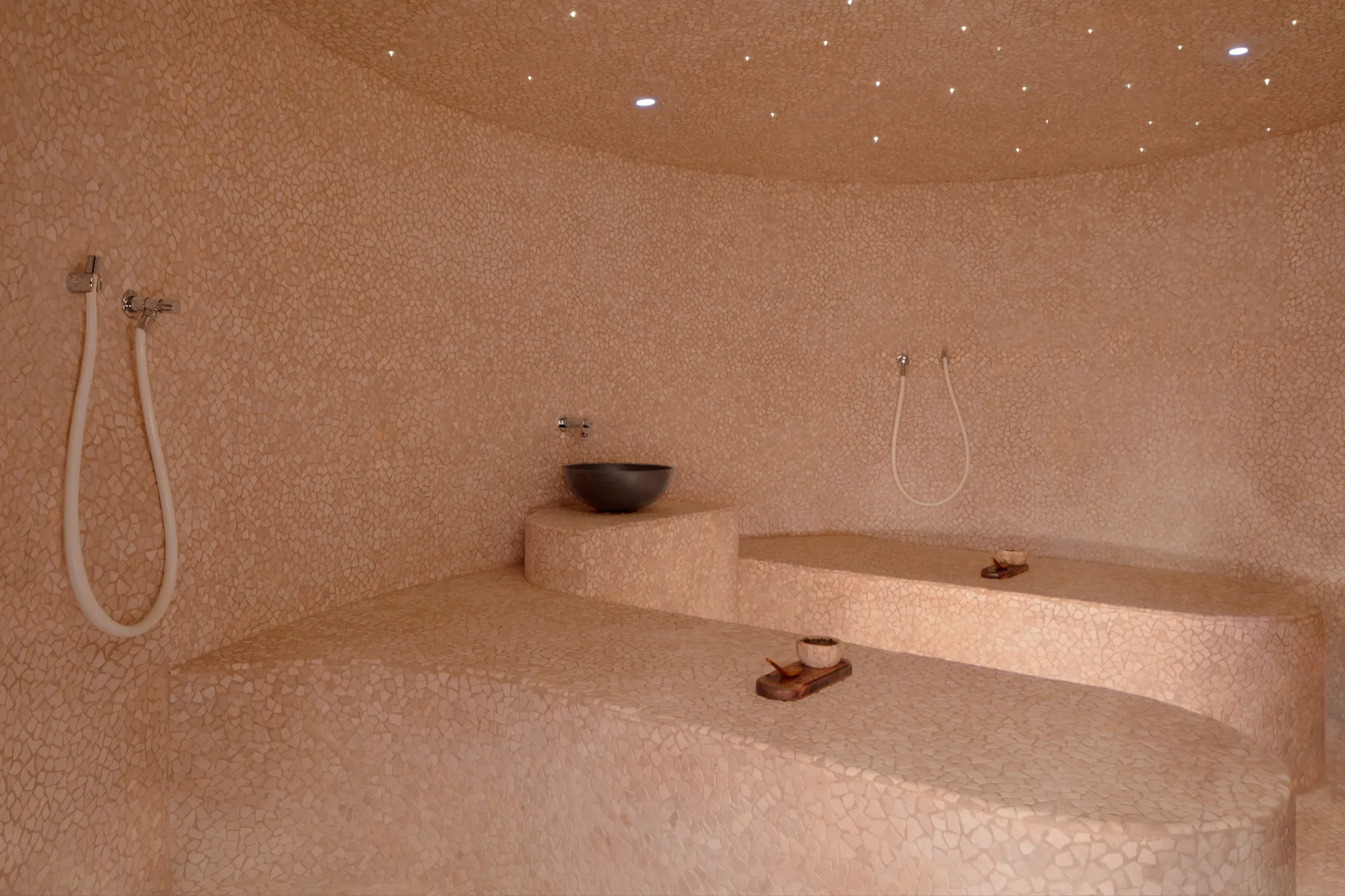 Warm-toned hammam steam room with tiled seating and ambient lighting at Impression Isla Mujeres by Secrets.