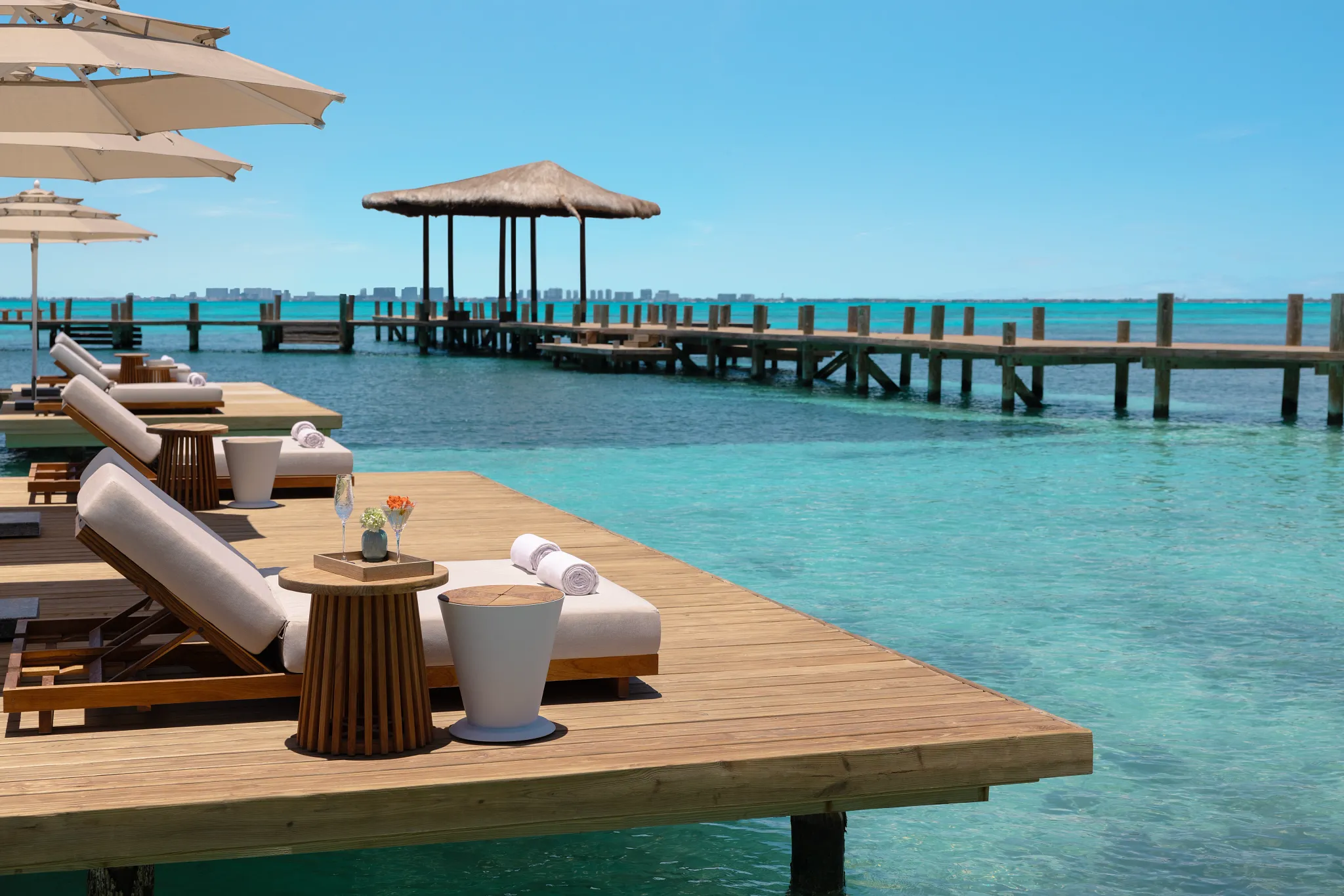 Overwater lounge deck with sunbeds and turquoise water at Impression Isla Mujeres by Secrets.