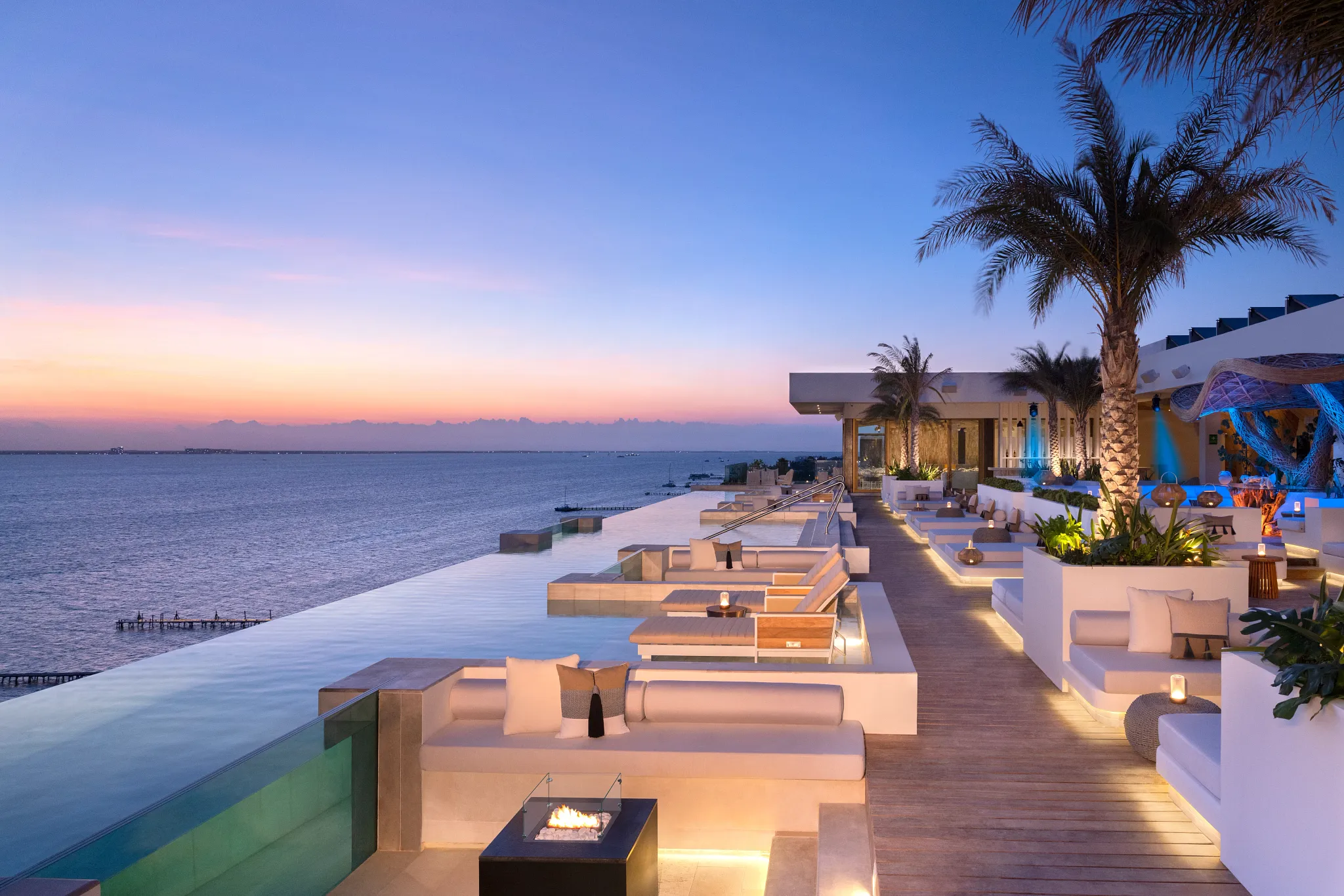 Rooftop infinity pool at sunset with ocean views and lounge seating at Impression Isla Mujeres by Secrets.
