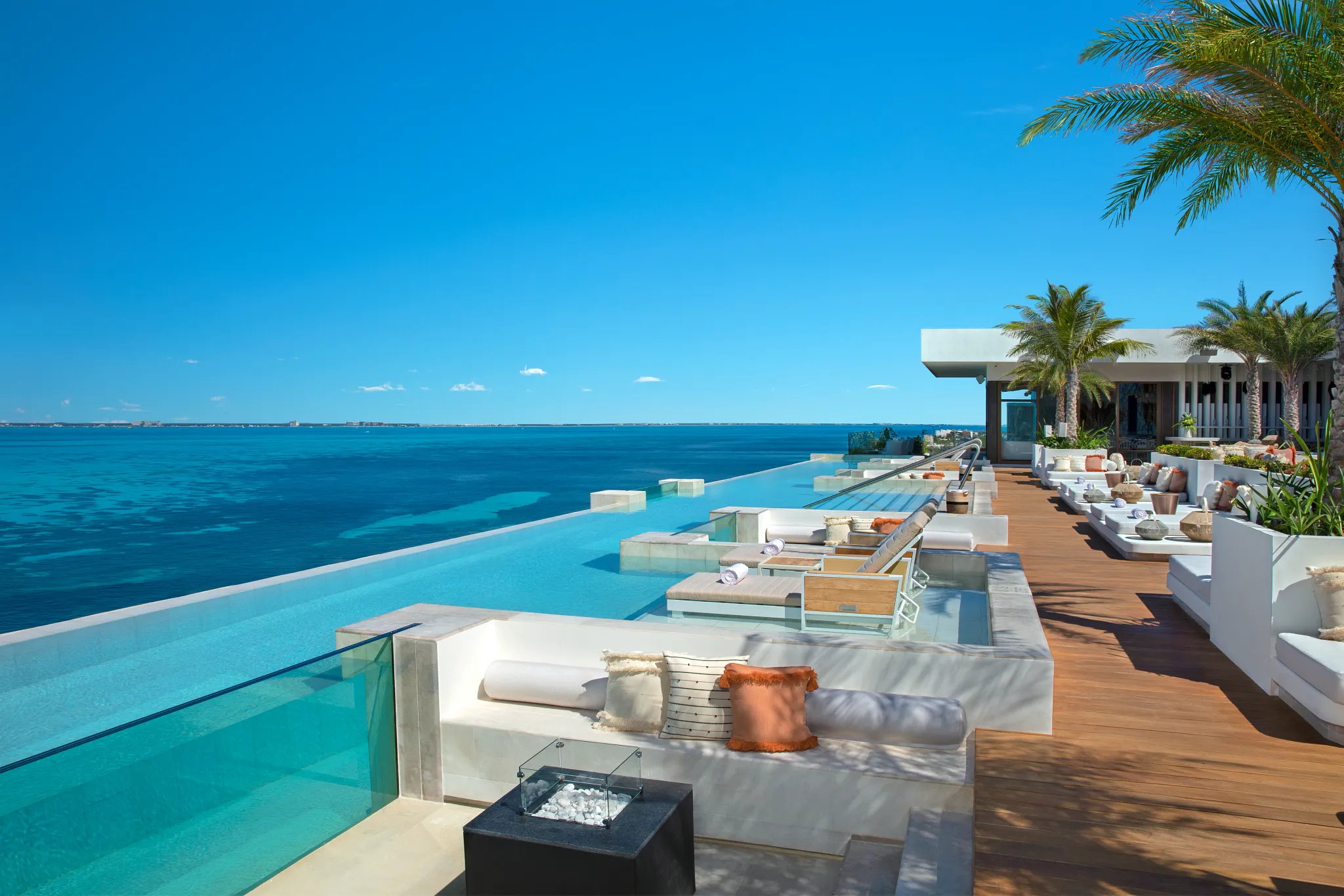 Rooftop infinity pool with lounge seating and ocean view at Impression Isla Mujeres by Secrets during the day.