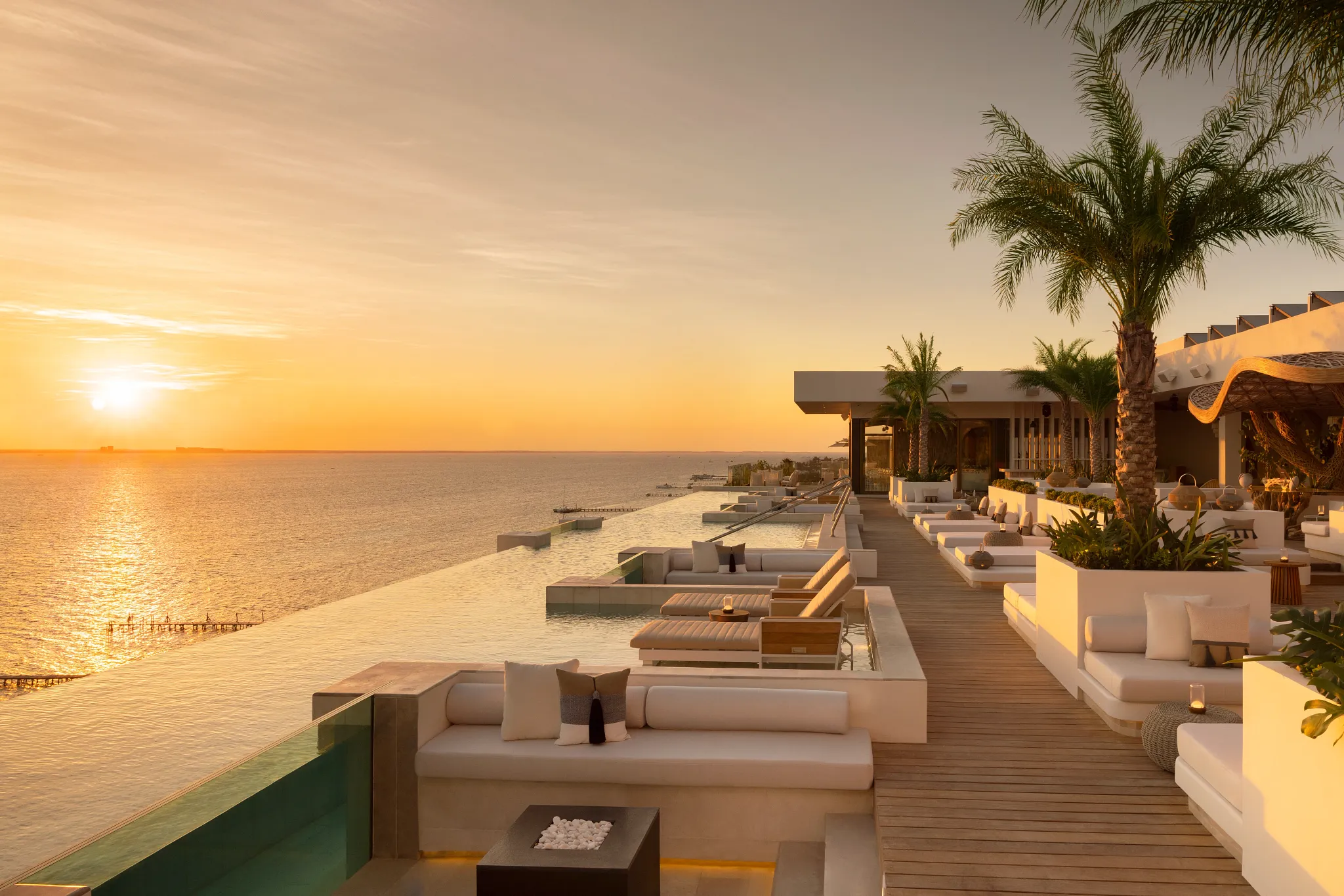 Rooftop infinity pool at sunset with lounge seating overlooking the Caribbean Sea at Impression Isla Mujeres by Secrets.