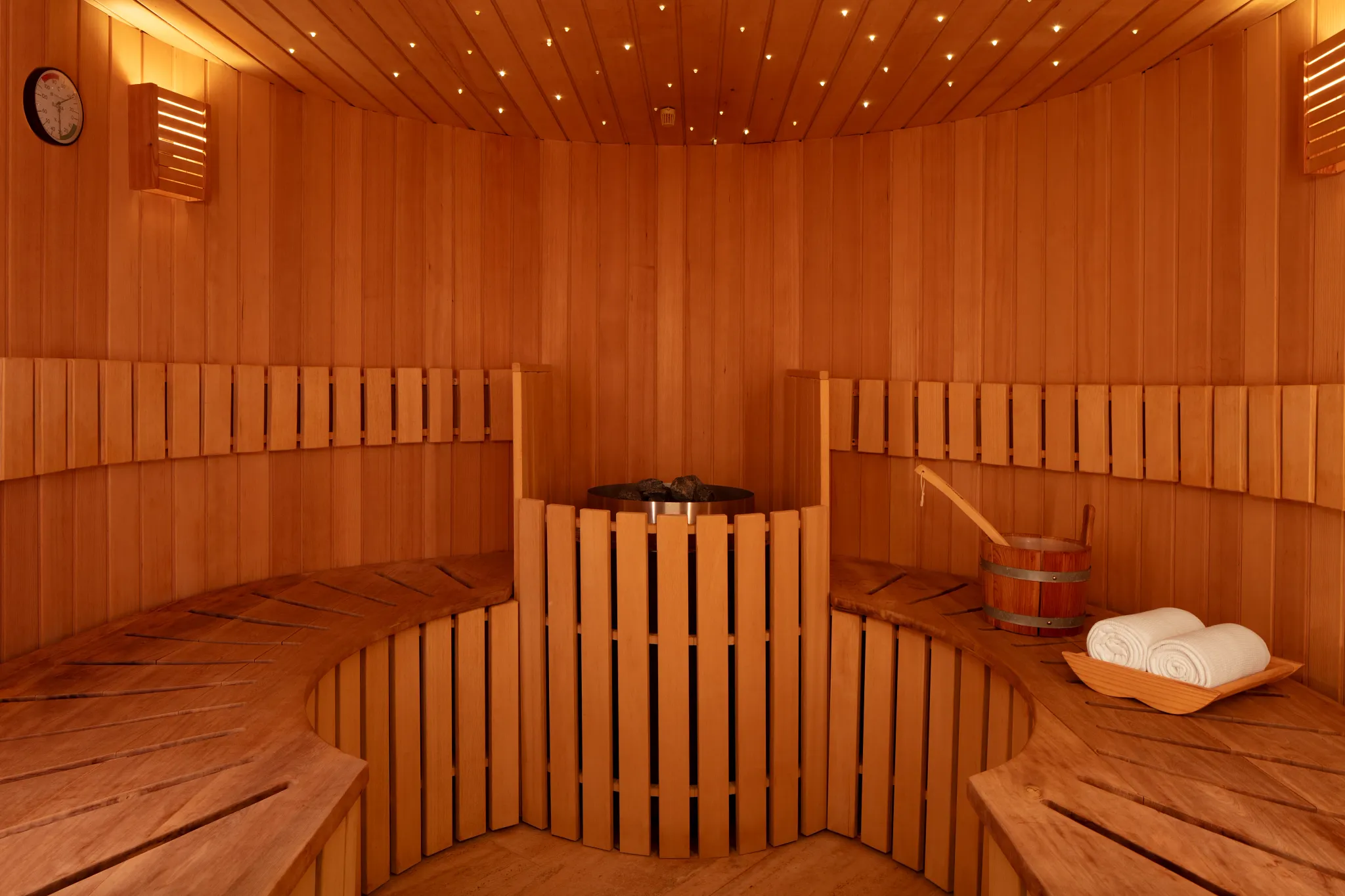Wooden sauna room with benches and central heater at Impression Isla Mujeres by Secrets.