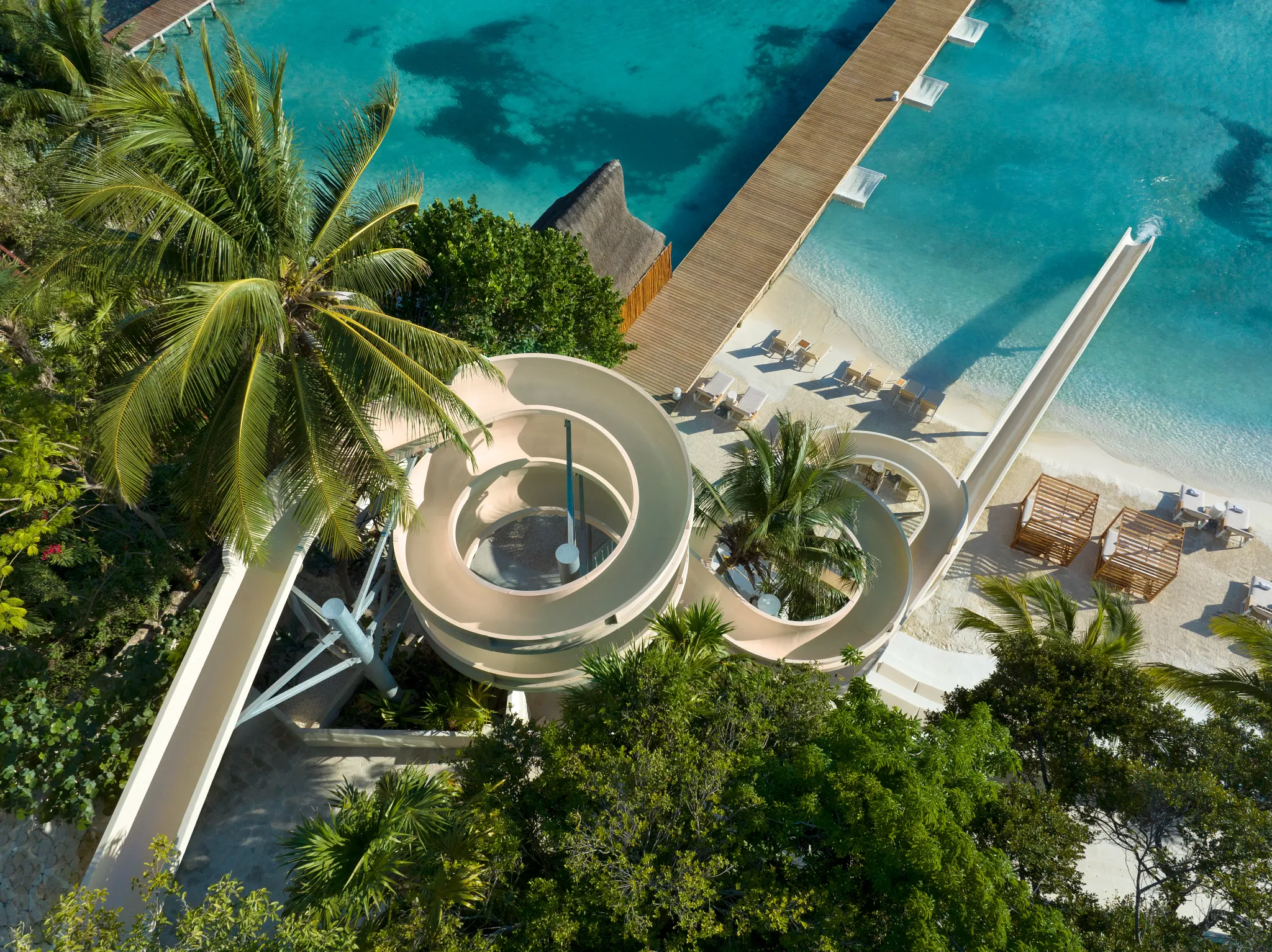 Spiral waterslide surrounded by tropical greenery leading to beach area at Impression Isla Mujeres by Secrets.